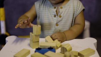 crianças jogar com de madeira brinquedos dentro a crianças sala. mãos do criança jogando a de madeira quadra jogos é uma caminho para aprender e desenvolve uma caminho do pensando sobre conceitos. potencial e a cérebro. video