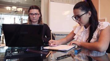 dois o negócio lindo o negócio mulheres trabalhando em uma o negócio projeto dentro a escritório sentado às uma escrivaninha usando uma computador. video