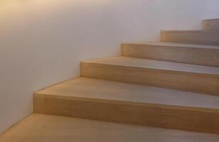 Wooden stairs leading upwards illuminated from the side photo