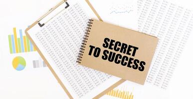 Secret to Success message on notebook with financial charts and data sheets photo