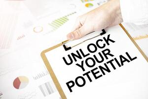 Unlock Your Potential written on clipboard over business charts and graphs. photo