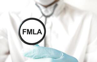 aumentador vaso con FMLA texto retenida por médico en laboratorio abrigo. médico salir y cuidado de la salud concepto foto