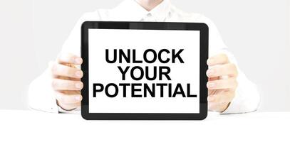 Unlock your potential message on tablet screen held by hands on white background photo