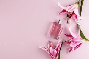 Transparent bottle of women's perfume or on pastel background with garden delicate lilies. Presentation of a floral fragrance. Top view. A copy space. photo