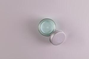 Top view of an open jar of a cosmetic product with a delicate blue texture for everyday face and body skin care. spa. massage. Gray background photo