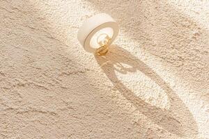 Chic wedding composition of two golden wedding rings on a concrete round podium on a concrete relief background and rays of the sun. A copy space. photo