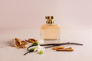 perfume bottle with gold cap with a luxury aroma of vanilla and tobacco notes on a beige stone background with natural vanilla sticks and tobacco photo