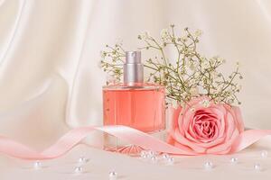 Elegant bottle of cosmetic spray, perfume on beige satin fabric with delicate rose, white pearls and a satin ribbon. Product presentation. Blank lay photo