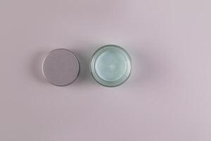Top view of an open jar of a cosmetic product with a delicate blue texture for everyday face and body skin care. spa. massage. Gray background. photo