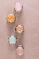 Set of cosmetic cream of various colors in glass jars on beige stone background. Top Vertical view. of the space. Layout for product advertising photo
