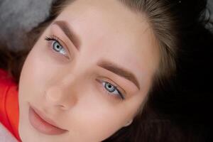 Beautiful girl with blue eyes poses after permanent eyebrow makeup. PMU Procedure, Permanent Eyebrow Makeup. photo