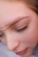 Macro photo of the model's eyebrows on which the sketch for permanent makeup is applied. PMU Procedure, Permanent Eyebrow Makeup.