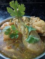 Fried chicken in curry sauce with coriander on black background photo