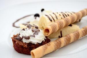 Chocolate wafers with whipped cream and chocolate syrup on white background photo