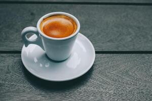 Espresso coffee cup on wooden table, vintage filter effect. photo