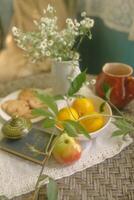 Still life with a cup of tea, lemon, apple and daisies photo