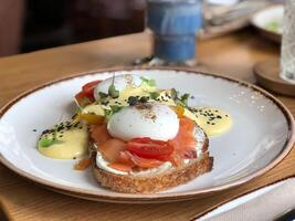 Poached egg on toast with salted salmon, tomatoes and basil photo