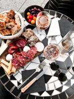 Italian antipasti wine snacks set. Cheese variety, Mediterranean olives, Prosciutto di Parma, salami and wine in glasses over black marble table photo