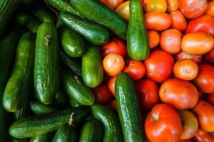 Cucumbers and tomatoes on the counter of a farmers market. photo