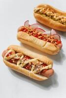 caliente perros con salsa de tomate, mostaza y mayonesa en blanco antecedentes foto