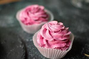 magdalenas con rosado crema en un oscuro fondo, selectivo atención foto