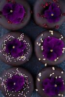 chocolate trufas con pensamiento flores en oscuro antecedentes. foto