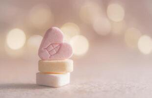 Pink and white marshmallows in the shape of a heart on a light background photo