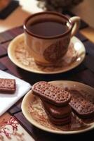 taza de té y chocolate galletas en de madera mesa, de cerca foto