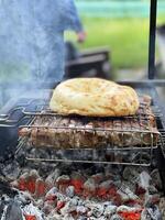 al aire libre parilla. carne y Agave un pan en un parrilla terminado caliente carbones foto