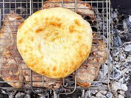 al aire libre parilla. carne y Agave un pan en un parrilla terminado caliente carbones foto