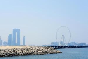 un sereno ver de el frente al mar en Dubái, presentando el silueta de un grande ferris rueda en contra un brumoso cielo. Dubái, uae - agosto 15, 2023 foto