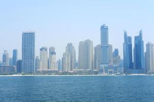 Dubai Marina's impressive skyline looms over calm blue waters, reflecting the city's modernity. Dubai, UAE - August 15, 2023 photo