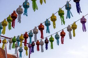 A view from below of colorful lantern flags hanging on strings of lights. photo