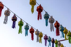 A view from below of colorful lantern flags hanging on strings of lights. photo