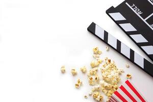 Clapperboard or movie slate black color with popcorn on white background. Cinema industry, video production and film concept. photo