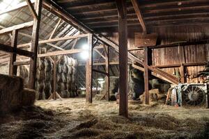 dentro rústico de madera antiguo granero heno fardos Paja luz de sol rayos ligero vigas granja foto