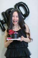 Beautiful woman wearing a black dress and chocolate cake in the concept of birthday photo