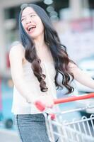 Asian woman pushing shopping cart in shopping mall photo