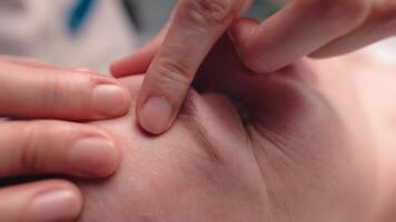 Close-up shot of a woman's head doing a facial massage on a treatment table. Therapist applying pressure with thumbs on forehead video