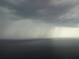 aéreo ver imágenes de lluvia nubes terminado mar Oceano negro nubes en malo clima día terminado mar superficie alto ángulo ver naturaleza vista. apocalipsis. tormenta grande carga oscuro melancólico lluvia nubes terminado un calma mar. foto