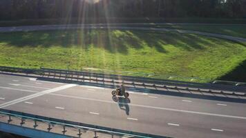 Mens Aan motorfiets schijven door een knooppunt zonsondergang tijd. antenne bijhouden dron schot. 4k. video