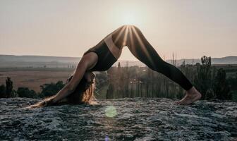 aptitud mujer. bien mirando medio Envejecido mujer con largo cabello, aptitud instructor en polainas y tapas haciendo extensión y pilates en el rock cerca bosque. hembra aptitud yoga rutina concepto. foto