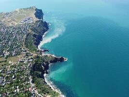 aéreo ver desde encima en calma azur mar y volcánico rocoso orillas pequeño olas en agua superficie en movimiento difuminar. naturaleza verano Oceano mar playa antecedentes. nadie. día festivo, vacaciones y viaje concepto foto