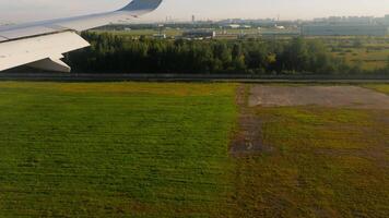 Footage of landing plane. View from inside through airplane window or porthole at asphalt of landing line and grey wing of air plane. Happy safe travel by aircraft concept. Welcome home video