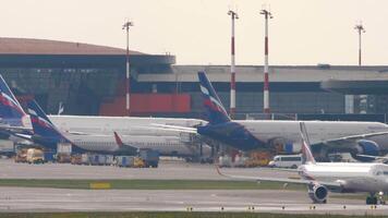 MOSCOW, RUSSIAN FEDERATION - JULY 30, 2021. Commercial aircraft of Aeroflot taxiing. Passenger plane on the taxiway. Jet airplane. Row of planes docking at the terminal. Tourism and travel concept video