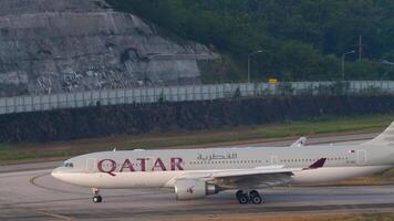 PHUKET, THAILAND - FEBRUARY 23, 2023. Commercial jet Airbus A330, A7-ACI of Qatar Airways taxiing, turning at Phuket airport. Shot of passenger aircraft on the taxiway, airfield video