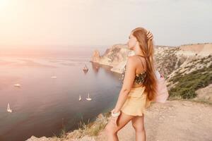 Woman travel sea. Happy tourist taking picture outdoors for memories. Woman traveler looks at the edge of the cliff on the sea bay of mountains, sharing travel adventure journey photo