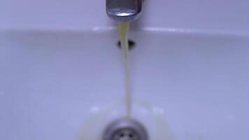 Dirty water flows from the tap. Yellow and brown tap water flows into the sink. Pollution of drinking resources. video