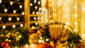 Two champagne glasses filled with champagne are placed on a table with a fruit arrangement. The glasses are surrounded by lights, creating a festive atmosphere. photo