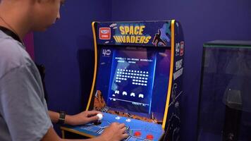 Space invaders Taito game machine. Simple Space Arcade in 8-bit retro video old game. Boy plays. Warsaw, Poland - July 28, 2023.